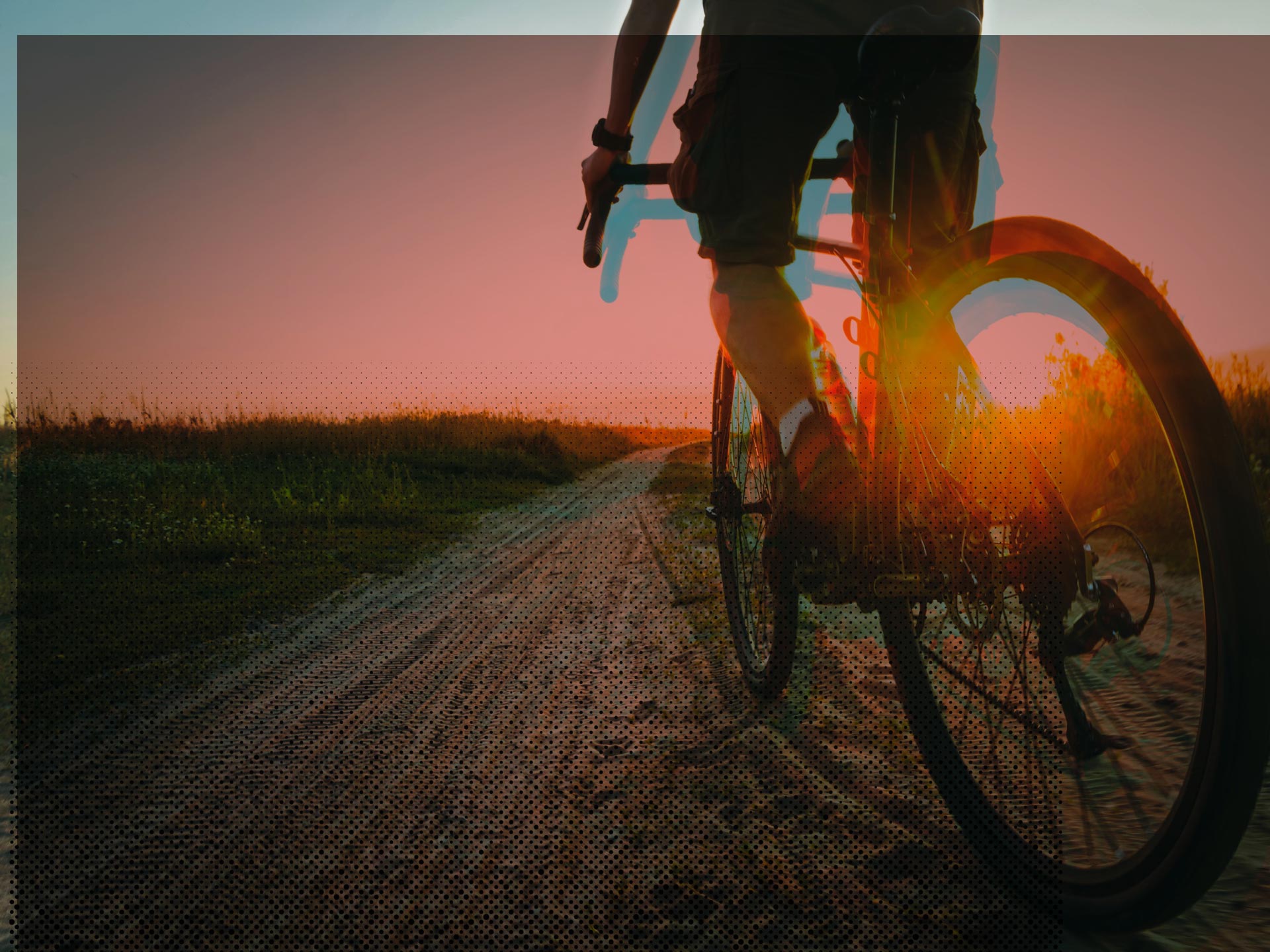 Radfahrer auf Feldweg bei stimmungsvollem Sonnenuntergang