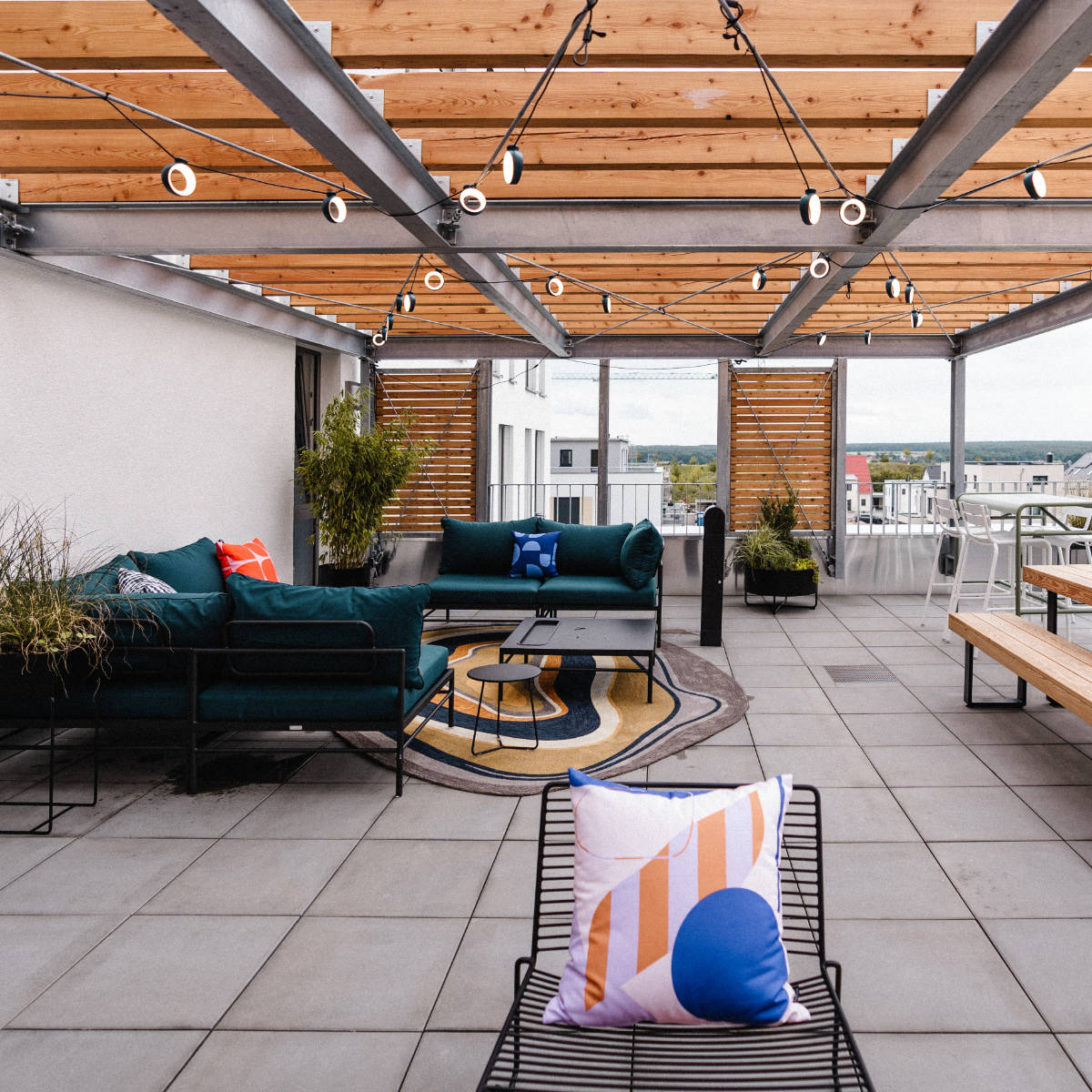 Überdachte Dachterrasse mit dunkelgrünen Sofas und Lichterketten